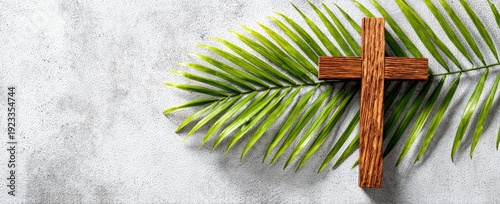 Wooden cross and palm branch rest on a textured, grey background