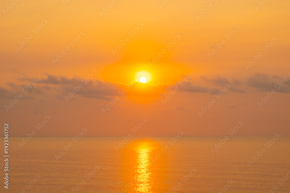 Obraz premium Nature sky breathtaking golden sunset over a calm ocean, with the entire sky and water bathed in brilliant shades of yellow and orange. Streaky clouds enhance the dramatic display of light 
