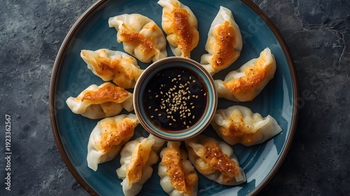 Delicious golden-brown pan-fried dumplings arranged in a circle with a savory soy dipping sauce, garnished with sesame seeds, perfect appetizer or flavorful snack