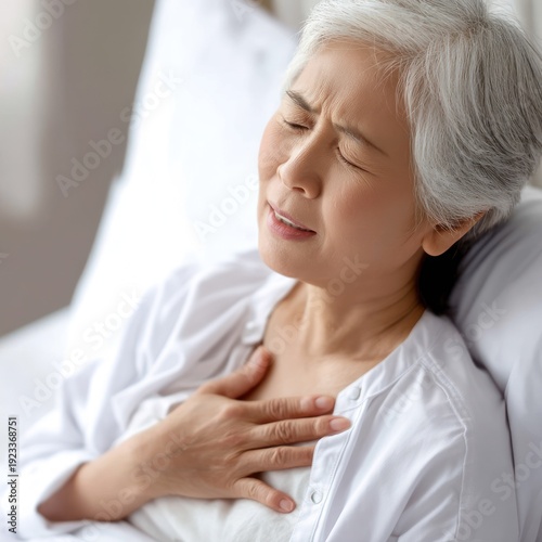 Close-up of elderly Asian patient lying in hospital bed with discomfort