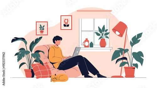 Young man relaxing in a bean bag chair while working on a laptop at home with houseplants and a cat for remote work concept.