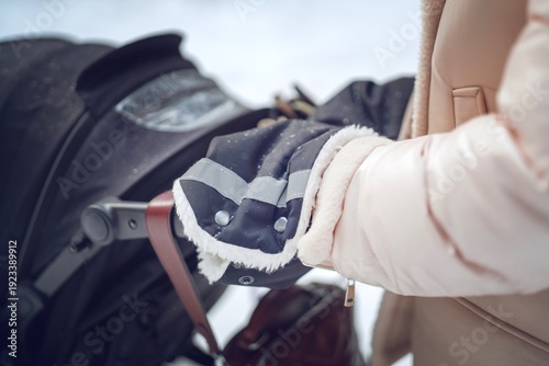 Wallpaper Mural Young mother's hands in a warm muff on a stroller handle while walking with baby in a snowy winter park. Outdoor family moment. Torontodigital.ca