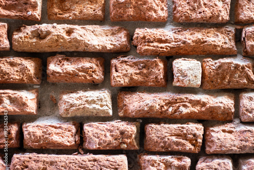 Obraz na plátne Textured red brick wall with varying sizes and shapes of bricks, showcasing a ru