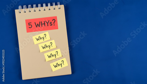 Spiral notebook with 5 whys problem solving sticky notes on blue background