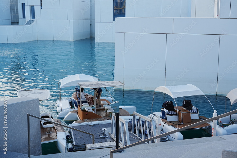 Fototapeta premium A stunning exterior view of the Louvre Abu Dhabi shows its floating dome shimmering above calm waterfront reflections.