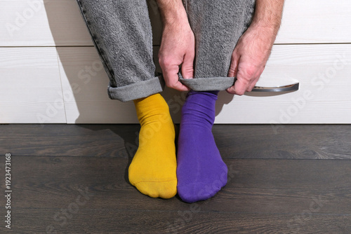 Photos Person adjusting jeans wearing mismatched yellow and purple socks, World Down Sy