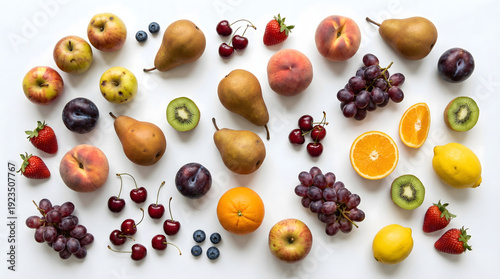 Assorted fresh fruits overhead on white background, including apples, pears, peaches, grapes, strawberries, blueberries, cherries, plums, kiwis, oranges, and lemons