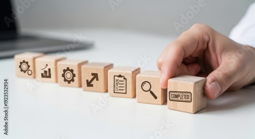 rocess standardization effort and showing cubes arranged in a uniform, repeatable sequence using wooden cubes, symbolic icons, human hand, natural depth of field, soft blurred background, minimal desk