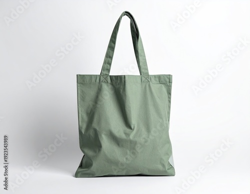 A sage green tote bag stands against a white backdrop, handles up