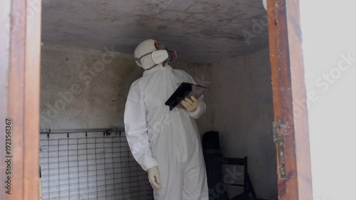 Photos Person in protective suit with respirator mask documenting hazardous conditions,