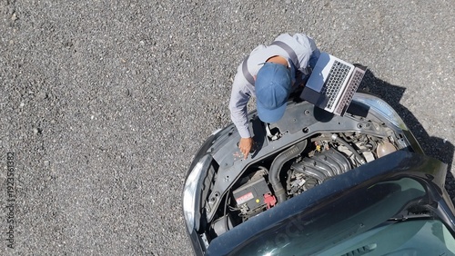 Fotografie Mechanic working on a vehicle, performing diagnostics and maintenance with a lap