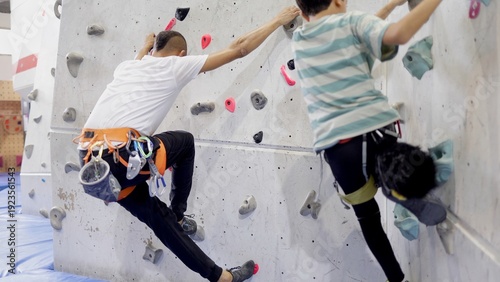 Φωτογραφία Father and son enjoying indoor rock climbing together, developing physical stren