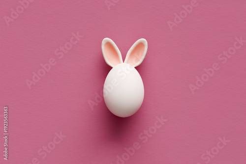 White egg with bunny ears on pink background for Easter