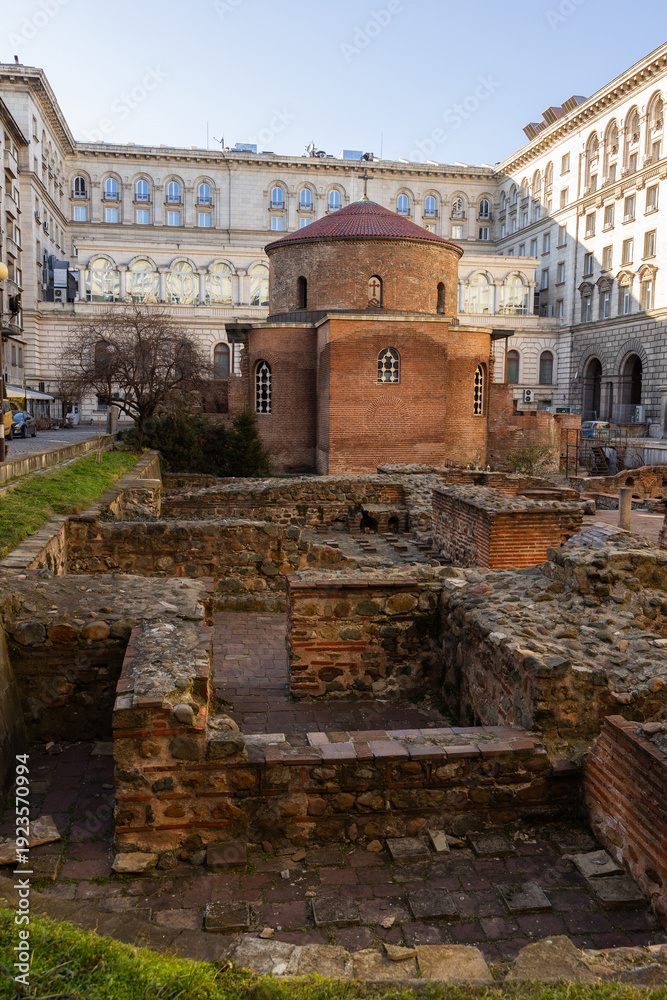 Fototapeta premium Red brick rotunda of St. George, Constantine Quarter, Sofia. Religious building within archaeological complex, ruins of ancient buildings and remains of paved street from Roman Empire..