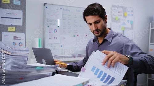 Paperwork and document for accounting of financial data during tax report research by a businessman working on a laptop in an office to manage complex law bureaucracy.