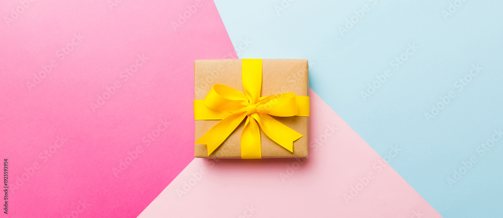 Obraz premium holiday paper present tied yellow ribbon bow top view with copy space. Flat lay holiday background. Birthday or christmas present. Christmas gift box concept with copy space