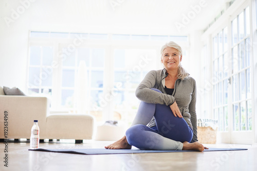Smiling senior woman doing exercise on mat in living room