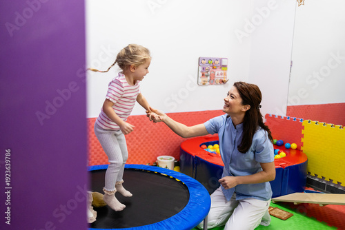 Photos Child practicing motor skills and balance on a trampoline with a professional pe