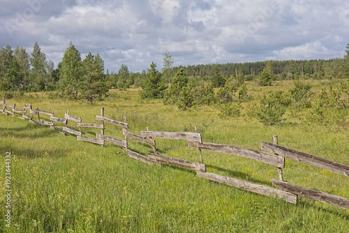 Traditional wooden fence in a rural landscape in cloudy summer weather, Saaremaa, Estonia, Europe.