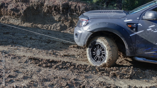 Fotografie Car stuck in mud and steel tow rope