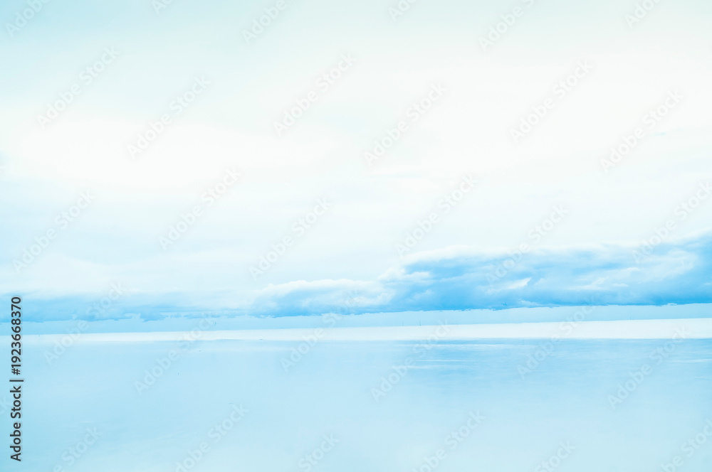 Fototapeta premium Serene blue seascape reflection under a light cloudy sky