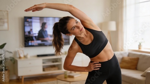 Young adult woman doing side stretch yoga at home living room, focused calm fitness routine, wellness and flexibility training for New Year goals and self care