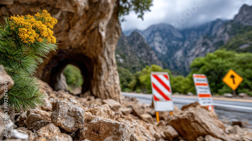Mountain road tunnel entrance blocked by rockfall with safety barricades and warning signs for road closure and emergency notification banner for transportation safety campaign
