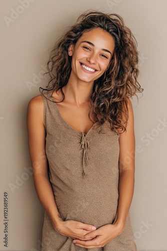 Young happy smiling pregnant woman holding hands isolated on plain beige background