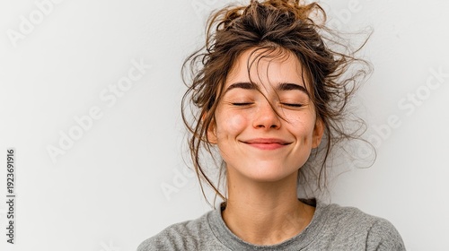 A girl smiles broadly, her eyes closed, against a white background. Lifestyle, different emotions, leisure concept