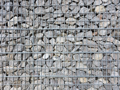 Gabion wall, a functional and modern architectural feature used for landscaping, erosion control, or decorative fencing, galvanized steel wire mesh grid,natural grey crushed stones.