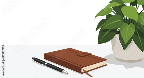 A closed brown leather notebook and black pen rest beside a potted green plant on a white desk.