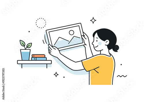 Young woman holding a framed landscape artwork, deciding where to hang it