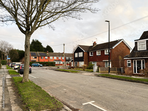 Foto Quiet suburban street in Manchester with red brick houses, trees, and parked car
