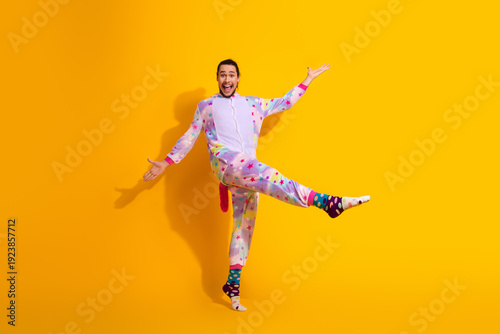 Canvastavla Playful man in colorful star pajama jumpsuit poses happily against bright yellow