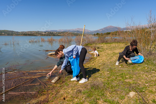 Volunteers collecting plastic waste from lake shore, conserving nature and promoting environmental cleanup efforts