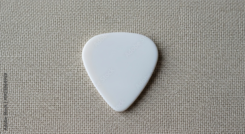 Fototapeta premium A plain white triangular guitar pick resting on a textured fabric background