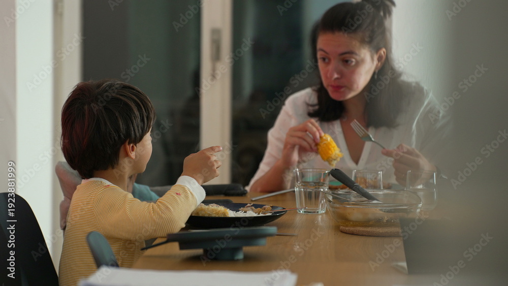 Fototapeta premium Mother and young boy sharing a conversation during family mealtime at a dining table, engaged interaction, nurturing bond, and relaxed indoor atmosphere