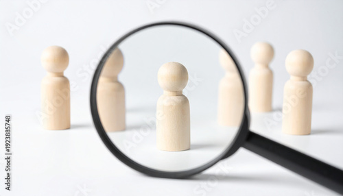 Magnifying glass focusing on manager wooden human figure among staff, HRM human resource management