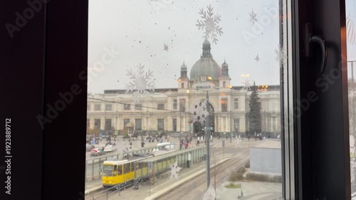 Lviv train station view through window with snowflakes, tram passing by, winter city scene Ukraine urban transport snowy day video.