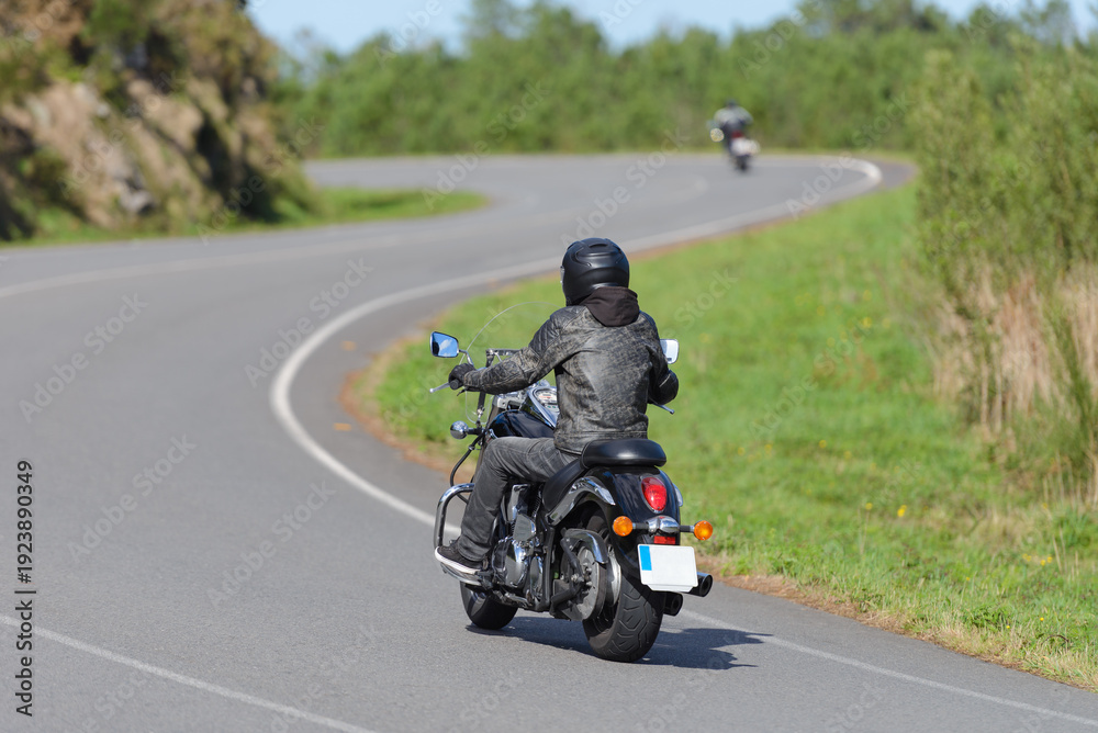 Obraz premium biker on a custom classic motorcycle rides down the road, road traffic