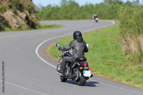 biker on a custom classic motorcycle rides down the road, road traffic
