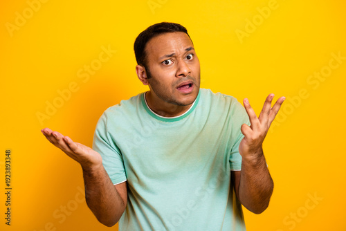 Young man puzzled expression gestures on bright yellow background for casual lifestyle