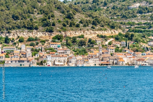 Croatia's island of Vis in Dalmatia. The historic town of Vis on a summer day. Mountains and forests, and the azure Adriatic Sea. Houses and church towers.