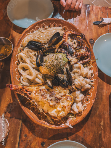 Mixed seafood platter with grilled lobster, octopus, mussels and calamari served on rustic wooden table in Holbox, Mexico.