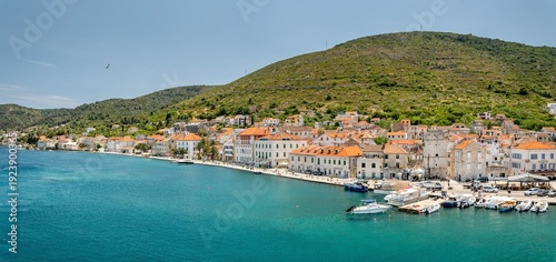 Croatia's island of Vis in Dalmatia. The historic town of Vis on a summer day. Mountains and forests, and the azure Adriatic Sea. Houses and church towers.
