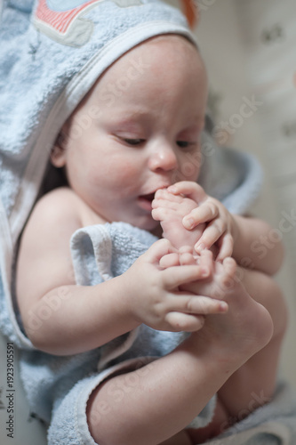 Photography In a warm and inviting space, a curious baby joyfully sucks on their thumb, wrapped snugly in a fluffy towel