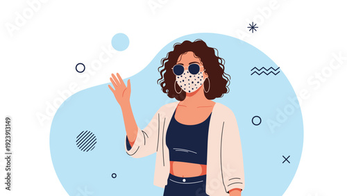 Stylish woman with curly hair and sunglasses waves hello while wearing a polka dot face mask for public safety.