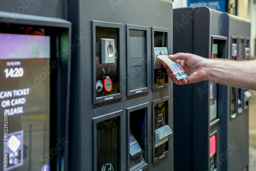 Photos Cash payment at automated parking meter, man inserting banknote into self-service parking terminal, modern urban infrastructure, smart parking system, city technology, public space services