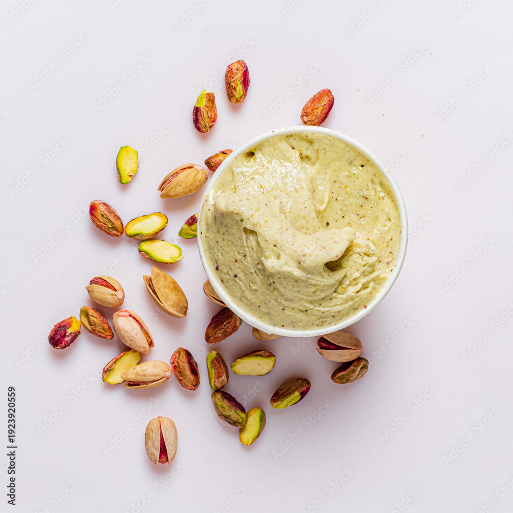 Fototapeta premium Delicious pistachio ice cream is surrounded by whole pistachio nuts, creating a tempting treat
