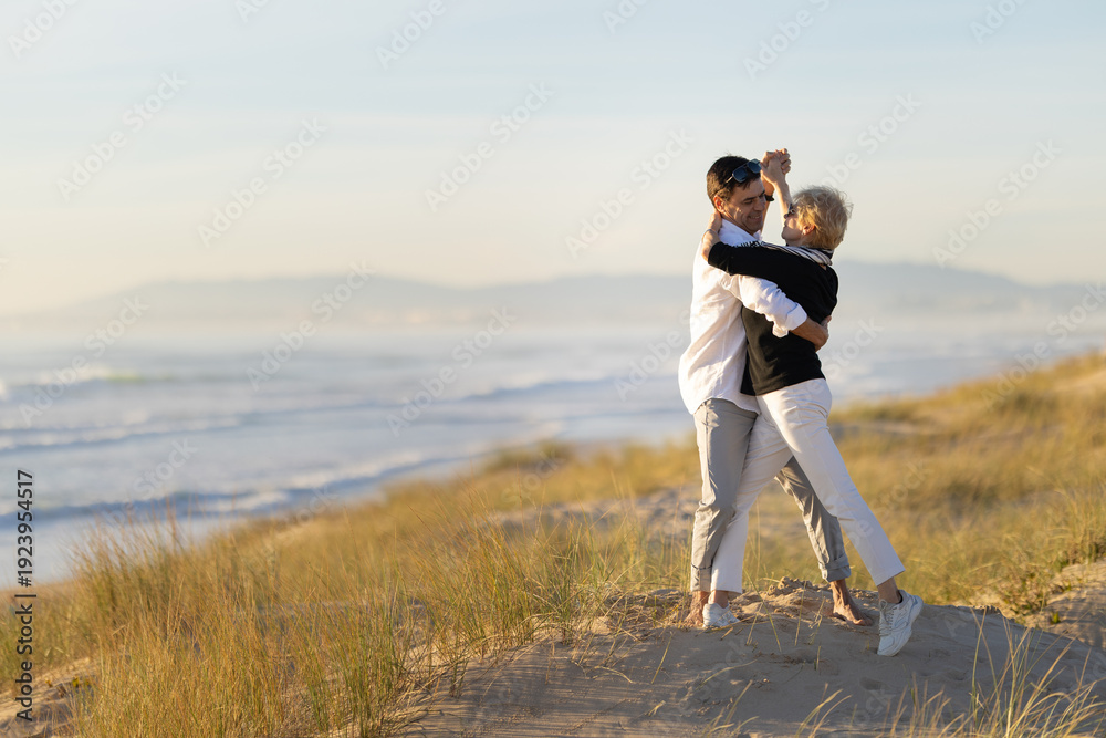 Fototapeta premium Couple dancing on sandy beach with ocean background
